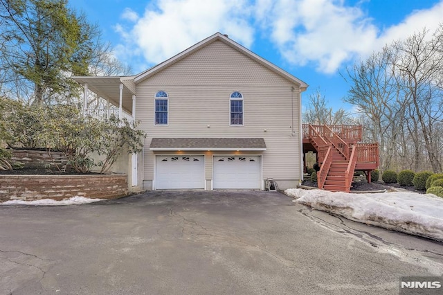 view of side of home featuring aphalt driveway, stairway, and a garage