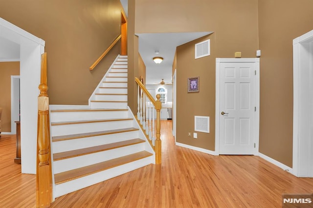 stairs featuring ceiling fan, wood finished floors, visible vents, and baseboards