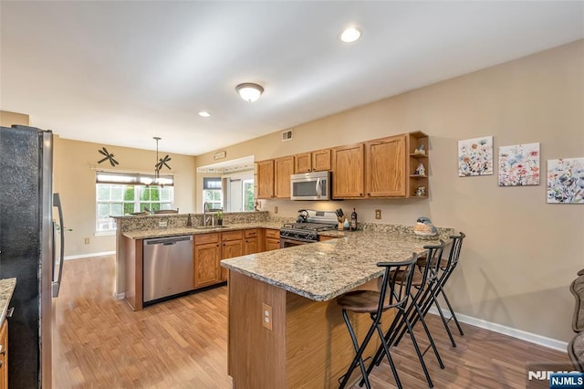 kitchen featuring decorative light fixtures, a kitchen breakfast bar, kitchen peninsula, and appliances with stainless steel finishes