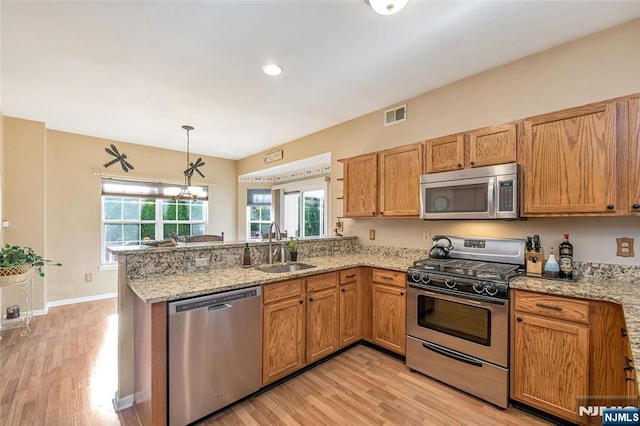 kitchen featuring sink, decorative light fixtures, kitchen peninsula, stainless steel appliances, and light stone countertops