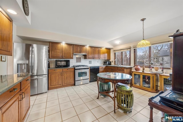 kitchen with decorative light fixtures, vaulted ceiling, dark stone counters, decorative backsplash, and black appliances