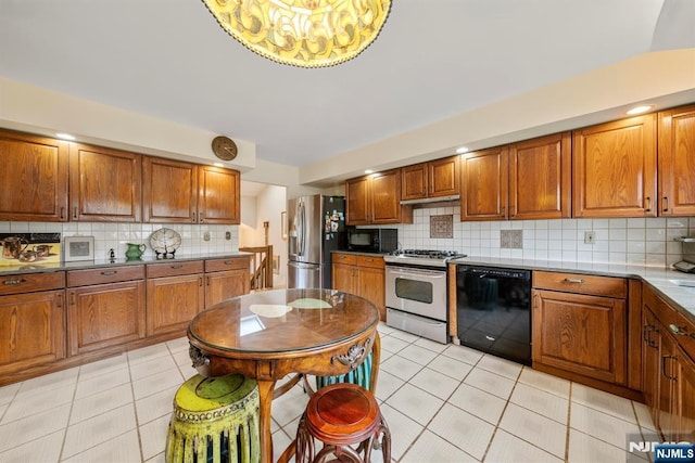 kitchen featuring backsplash, light tile patterned floors, and black appliances