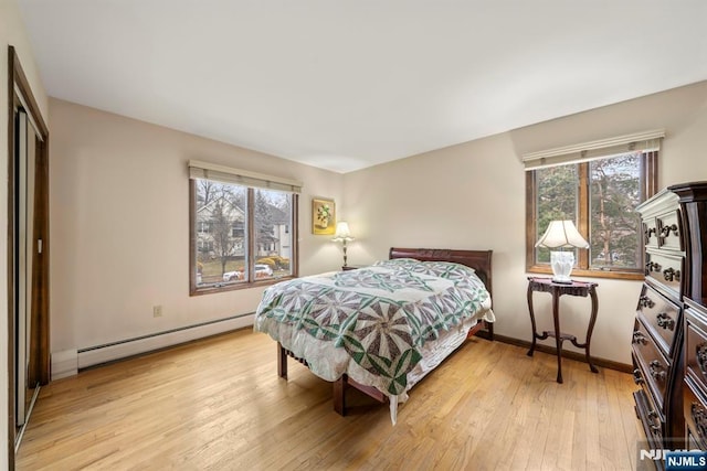 bedroom featuring baseboard heating, a closet, and light hardwood / wood-style flooring