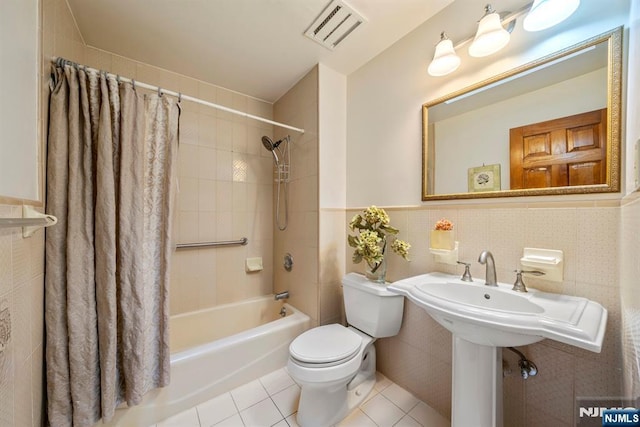 bathroom with tile patterned floors, toilet, tile walls, and shower / bath combo