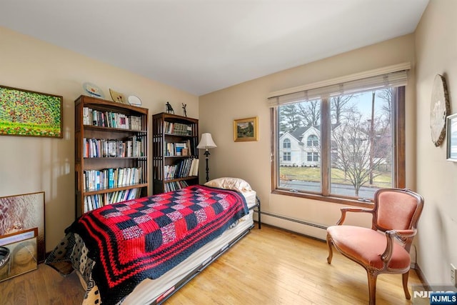 bedroom with a baseboard radiator and light hardwood / wood-style flooring