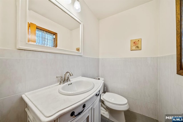 bathroom featuring tile walls, vanity, and toilet