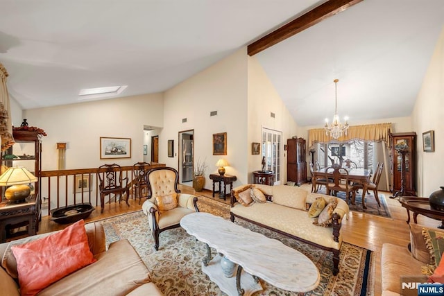 living room featuring lofted ceiling with skylight, a chandelier, and light wood-type flooring