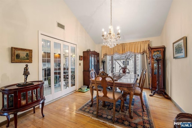 dining area featuring a chandelier, light wood-type flooring, and french doors