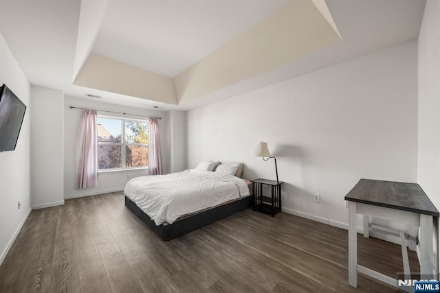 bedroom featuring dark hardwood / wood-style floors and a raised ceiling