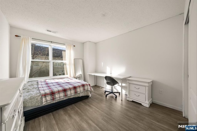 bedroom with dark hardwood / wood-style floors and a textured ceiling