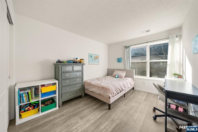 bedroom featuring light hardwood / wood-style flooring and a textured ceiling