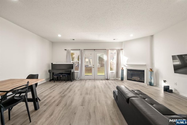 living room with french doors, a textured ceiling, and light wood-type flooring