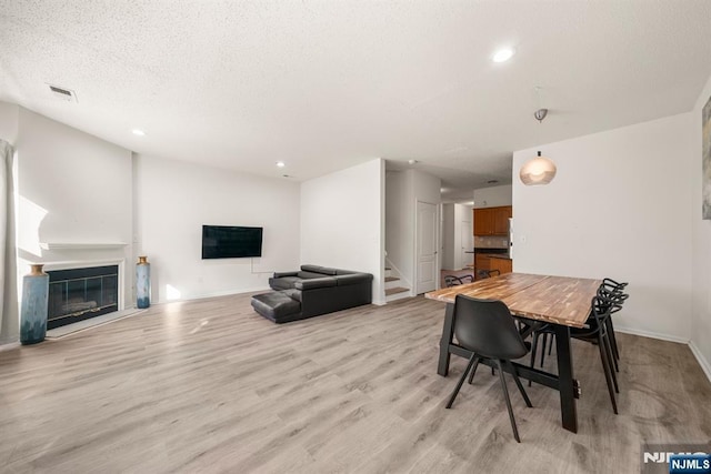 dining area featuring a textured ceiling and light hardwood / wood-style flooring