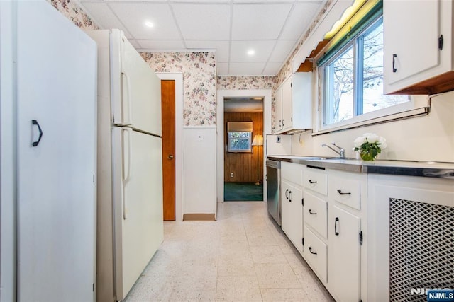 kitchen featuring sink, a paneled ceiling, stainless steel dishwasher, and white cabinets