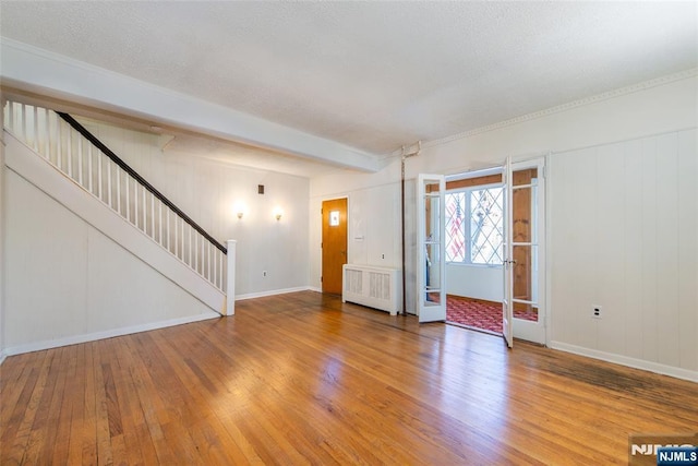 unfurnished living room with beamed ceiling, wood-type flooring, and radiator heating unit