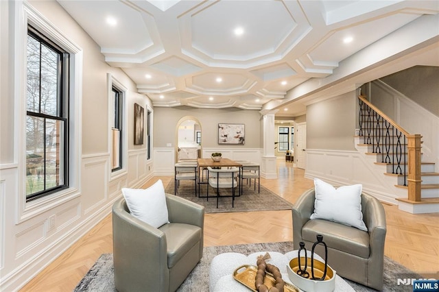 living room with coffered ceiling, decorative columns, and light parquet flooring