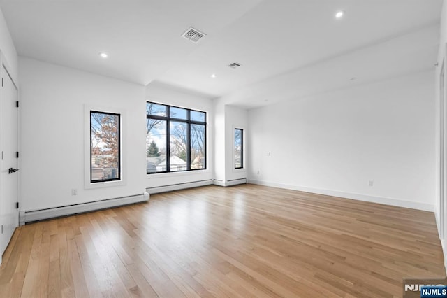 empty room with light hardwood / wood-style flooring and a baseboard heating unit