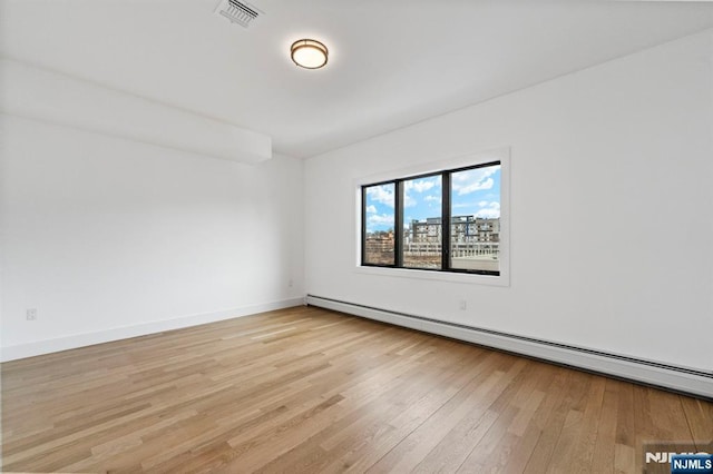 unfurnished room with a baseboard heating unit and light hardwood / wood-style flooring