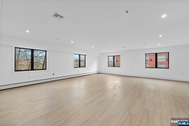 unfurnished room with baseboard heating and light hardwood / wood-style flooring