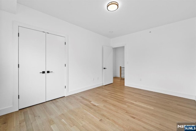 unfurnished bedroom with light wood-type flooring and a closet