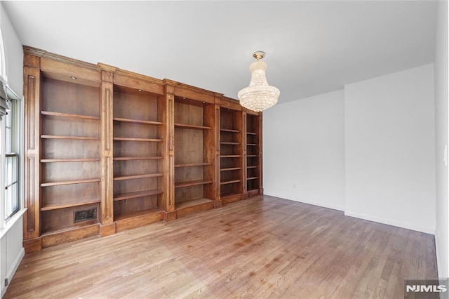 unfurnished room featuring an inviting chandelier and hardwood / wood-style floors