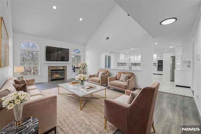 living room featuring a fireplace, high vaulted ceiling, and light hardwood / wood-style floors