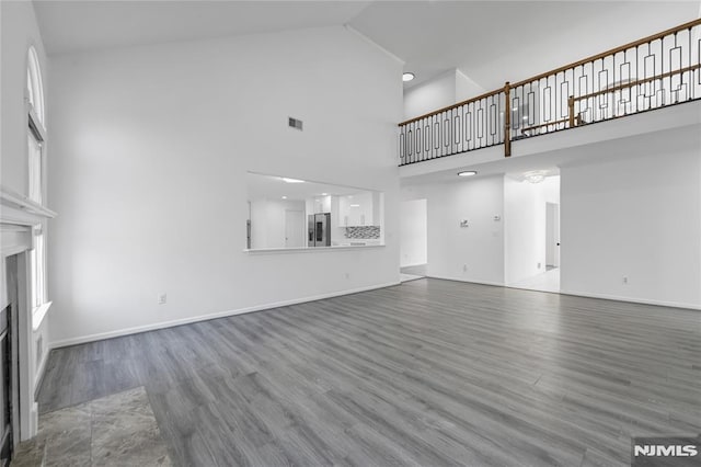 unfurnished living room with wood-type flooring and high vaulted ceiling