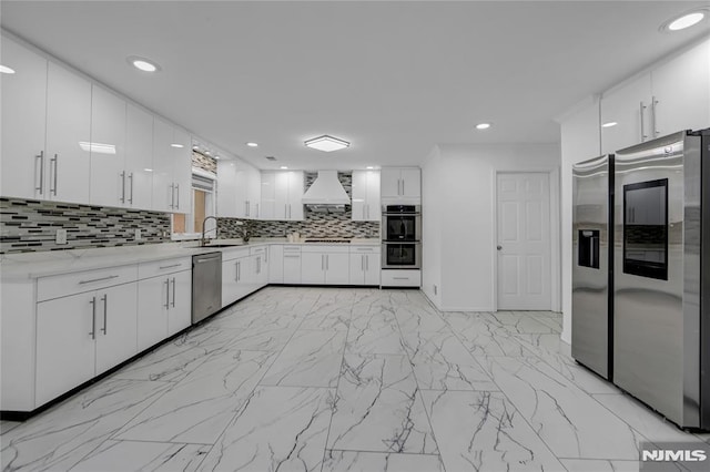 kitchen featuring premium range hood, sink, tasteful backsplash, appliances with stainless steel finishes, and white cabinets