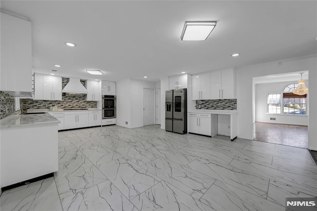 kitchen featuring appliances with stainless steel finishes, white cabinetry, backsplash, light stone countertops, and custom range hood