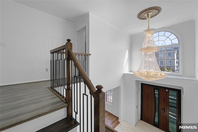 stairs featuring ornamental molding, a chandelier, and hardwood / wood-style floors