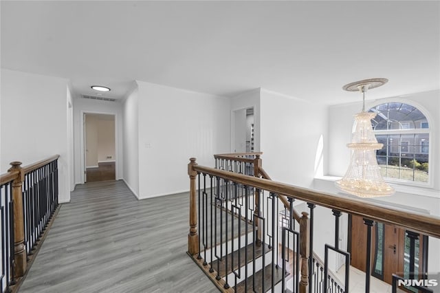 hall featuring hardwood / wood-style flooring, ornamental molding, and a notable chandelier