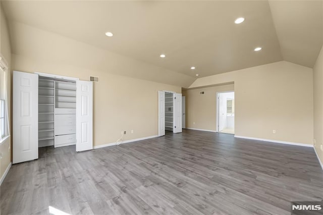 unfurnished bedroom with multiple closets, lofted ceiling, and light hardwood / wood-style flooring