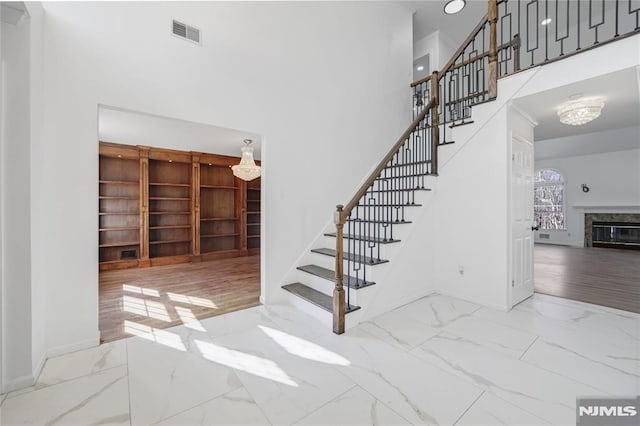 staircase featuring a towering ceiling and a fireplace