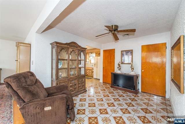 living room with ceiling fan and a textured ceiling