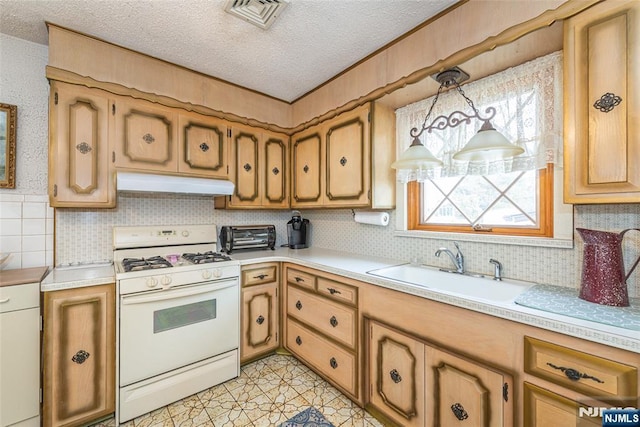 kitchen with sink, gas range gas stove, hanging light fixtures, a textured ceiling, and decorative backsplash