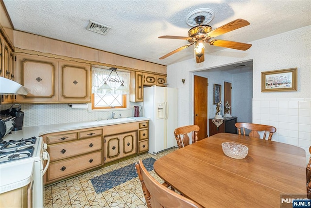 kitchen featuring sink, tile walls, white appliances, ceiling fan, and a textured ceiling