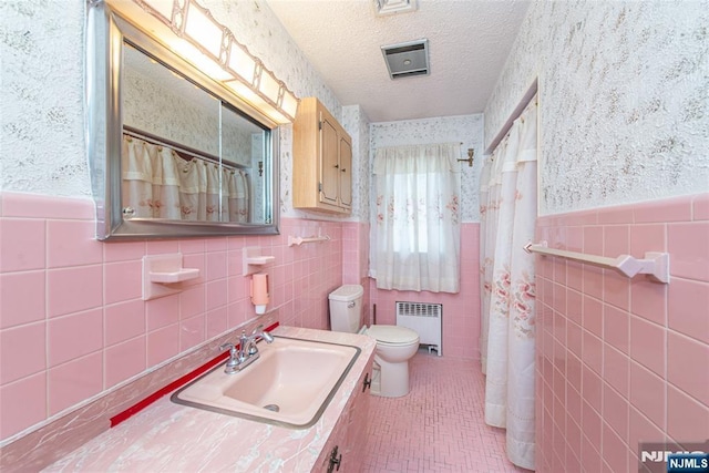 bathroom featuring radiator, vanity, a textured ceiling, tile patterned floors, and toilet