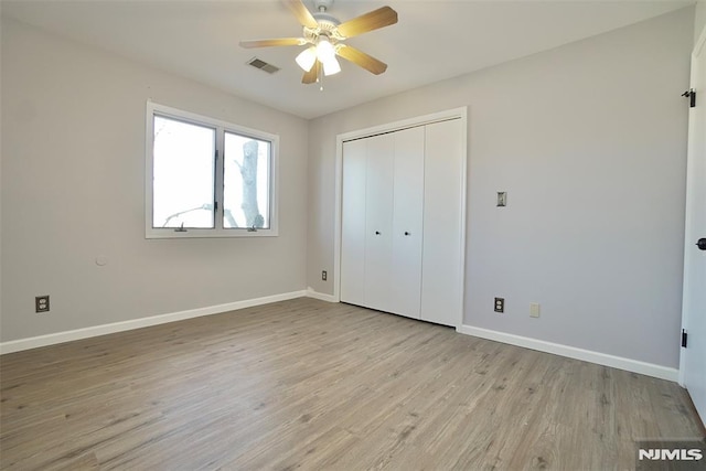 unfurnished bedroom with light hardwood / wood-style flooring, a closet, and ceiling fan