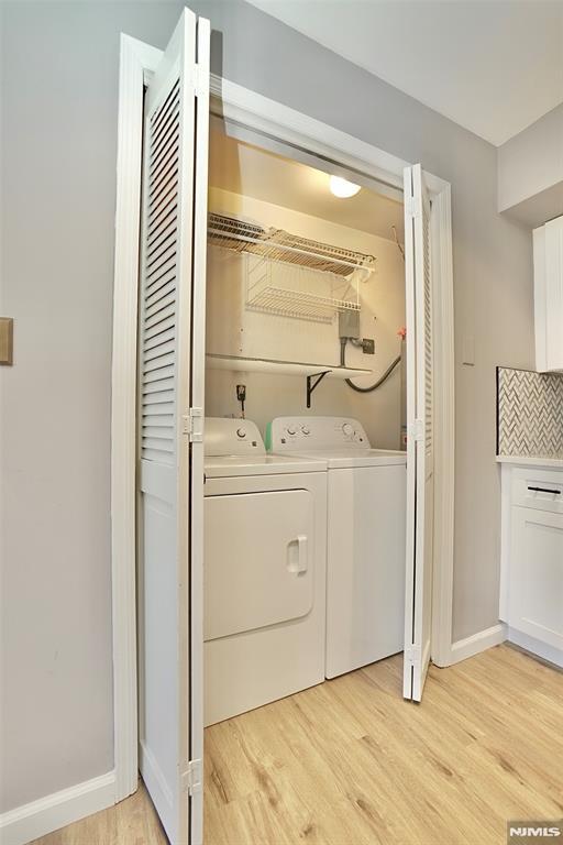 laundry area with separate washer and dryer and light hardwood / wood-style floors