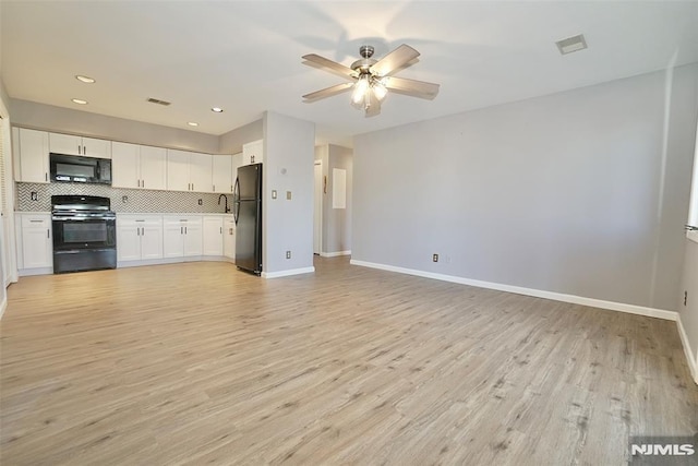 kitchen featuring tasteful backsplash, white cabinets, light hardwood / wood-style flooring, and black appliances