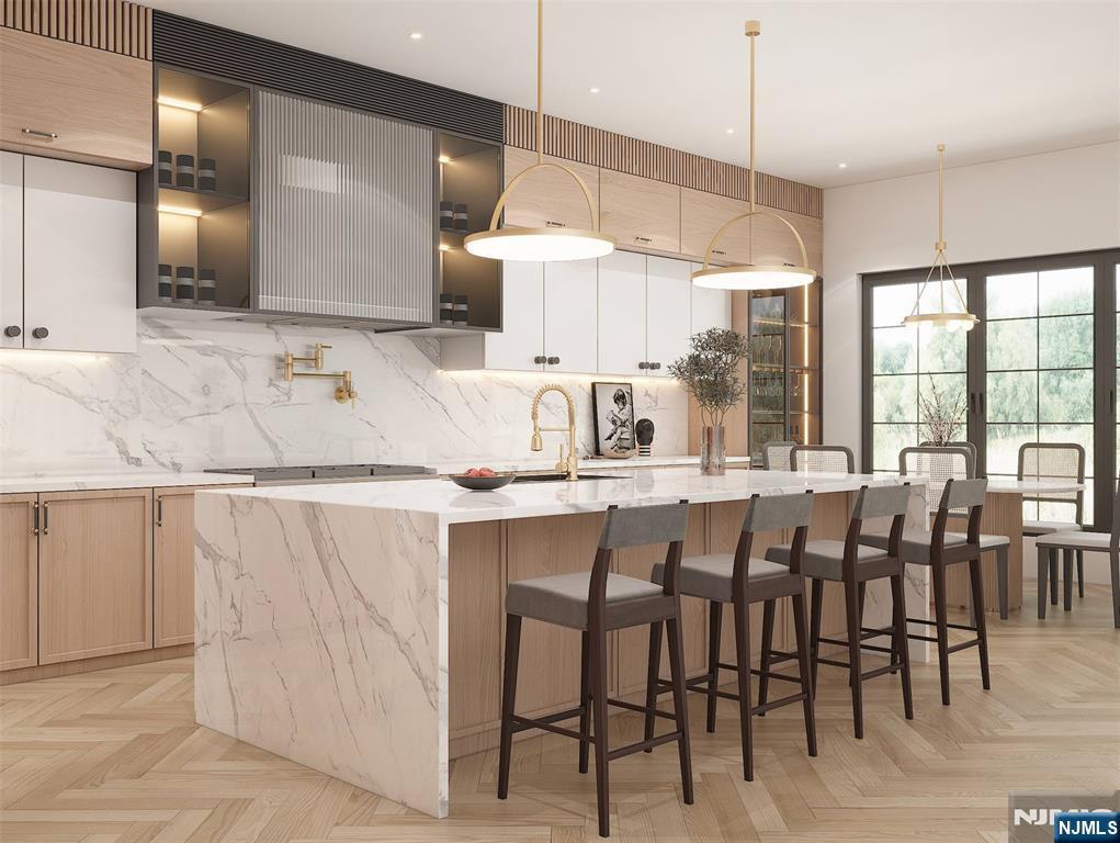 kitchen with stainless steel gas cooktop, backsplash, a sink, and a large island with sink