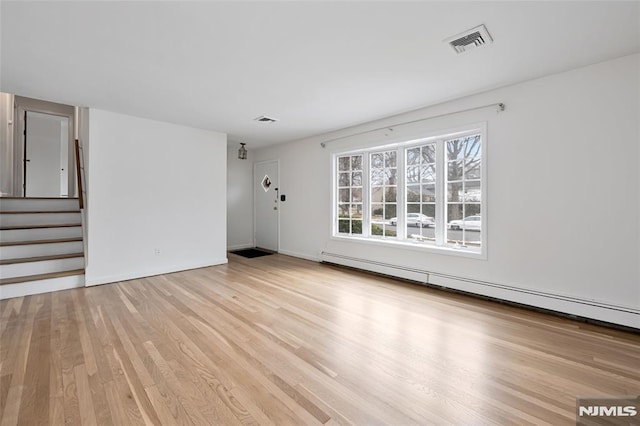 empty room featuring a baseboard radiator and light wood-type flooring