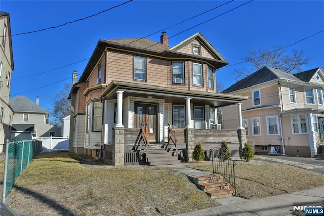 view of front of home featuring a chimney, fence, a porch, and french doors