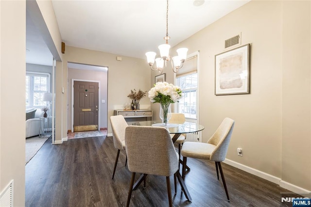 dining room with dark hardwood / wood-style floors and a notable chandelier