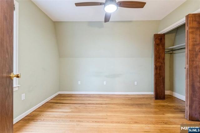 unfurnished bedroom featuring ceiling fan, lofted ceiling, a closet, and light wood-type flooring