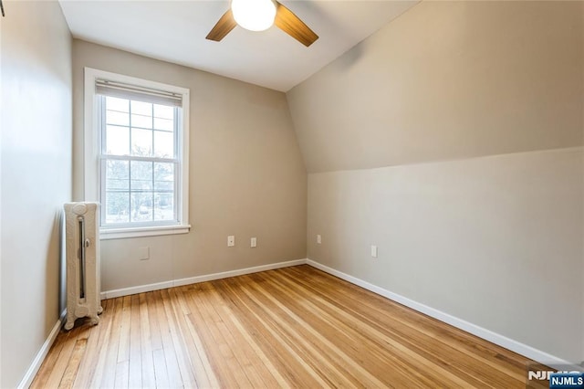 bonus room with radiator heating unit, vaulted ceiling, ceiling fan, and light wood-type flooring