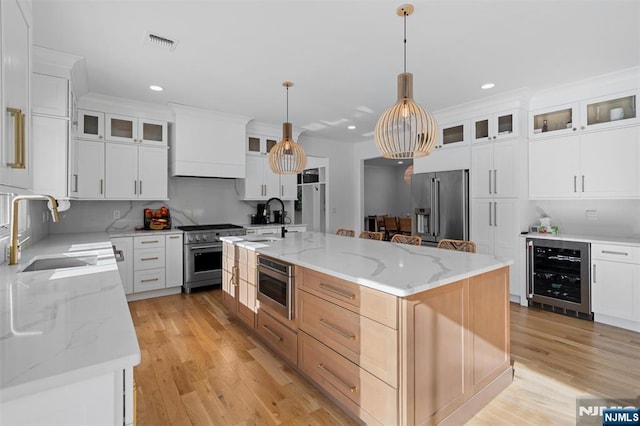 kitchen with white cabinets, high end appliances, a kitchen island, and beverage cooler