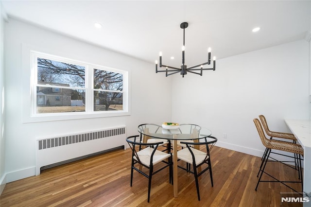 dining space featuring an inviting chandelier, radiator heating unit, and dark hardwood / wood-style flooring