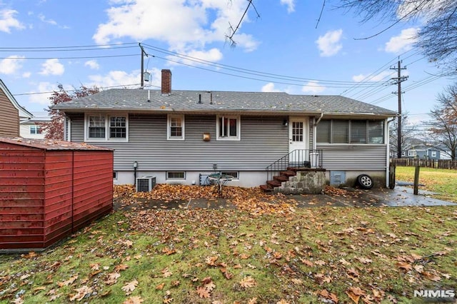 rear view of property with a shed, a sunroom, central AC unit, and a lawn