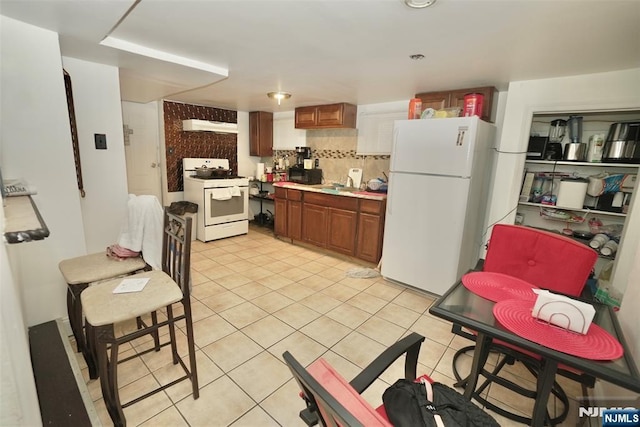 kitchen featuring white appliances, decorative backsplash, and light tile patterned floors